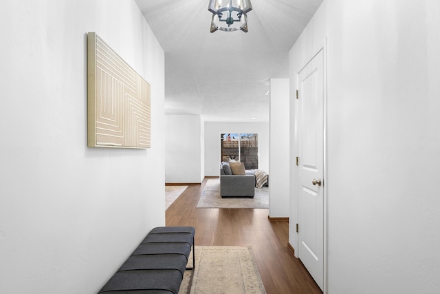 hallway with hardwood / wood-style flooring, a notable chandelier, and a textured ceiling