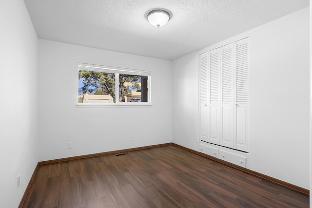 unfurnished bedroom featuring dark wood-type flooring, a closet, and a textured ceiling