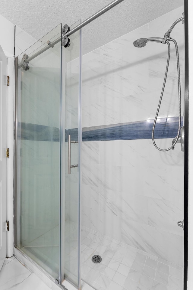 bathroom featuring a shower with door and a textured ceiling