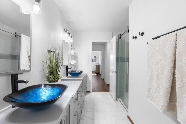 bathroom with vanity, a shower with door, and a textured ceiling