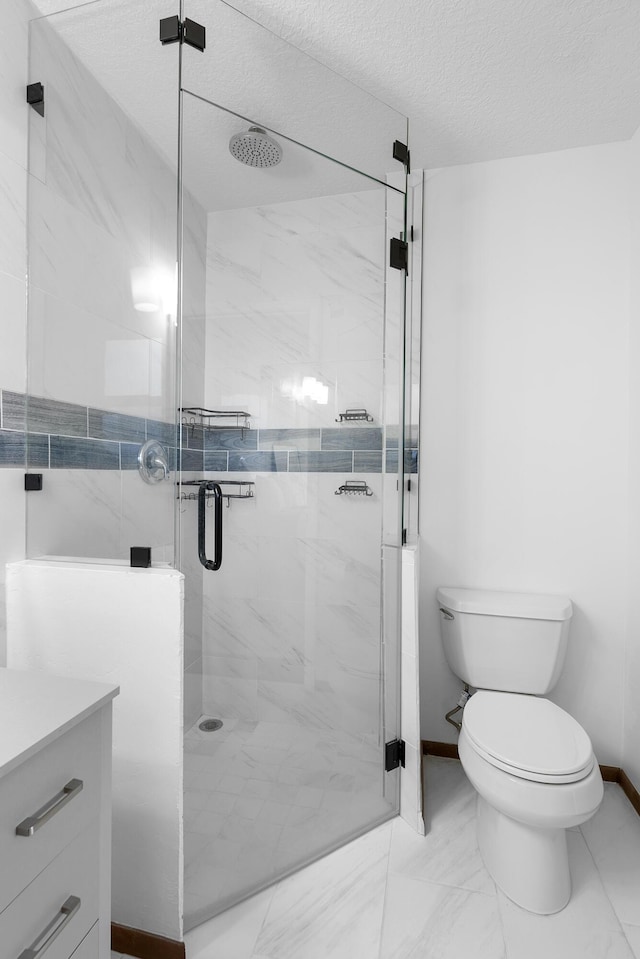 bathroom with vanity, toilet, a shower with door, and a textured ceiling