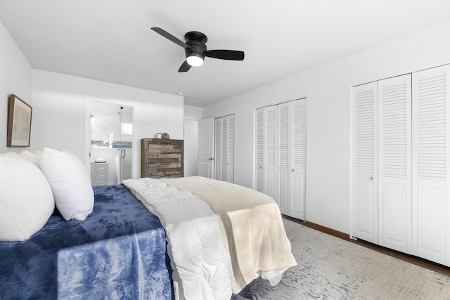 bedroom featuring ceiling fan, connected bathroom, hardwood / wood-style floors, and two closets