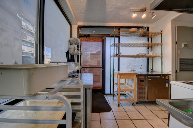 kitchen featuring light tile patterned floors, sink, dishwasher, refrigerator, and a textured ceiling