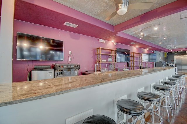 bar featuring ceiling fan, light stone countertops, dark wood-type flooring, and a textured ceiling