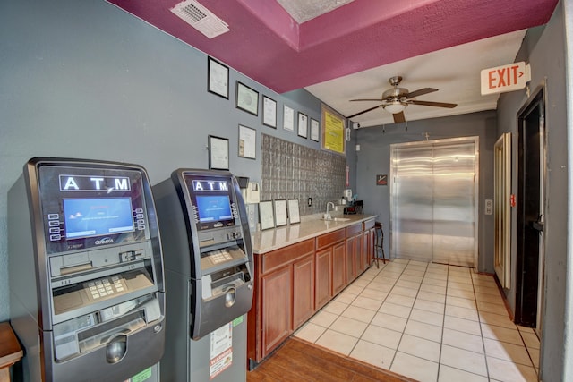 kitchen with sink, elevator, ceiling fan, and light tile patterned flooring