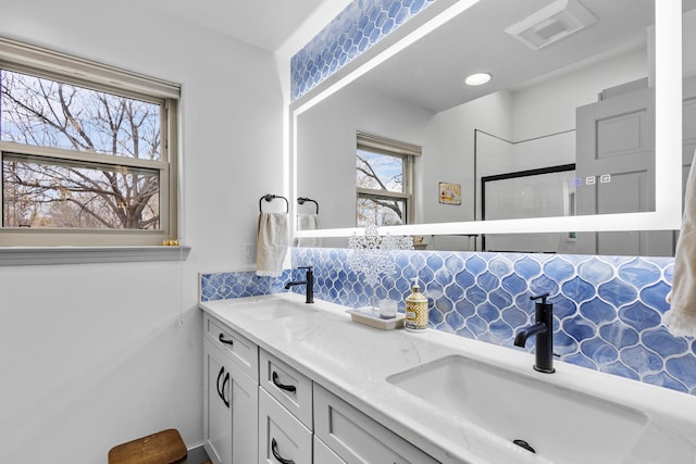 bathroom featuring a shower with door, vanity, and decorative backsplash