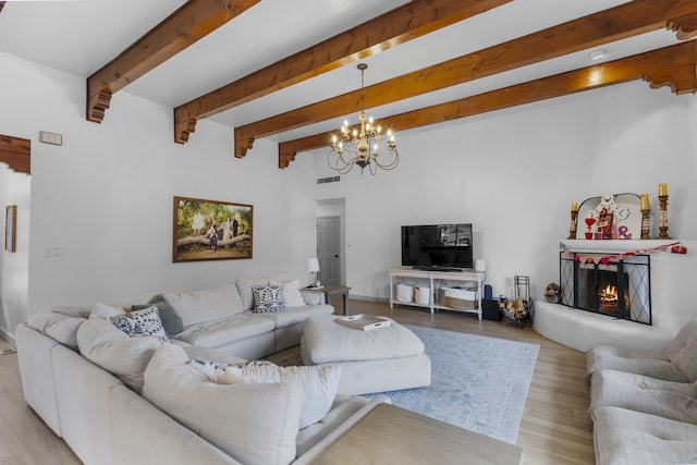 living room featuring beam ceiling, light hardwood / wood-style floors, and a chandelier