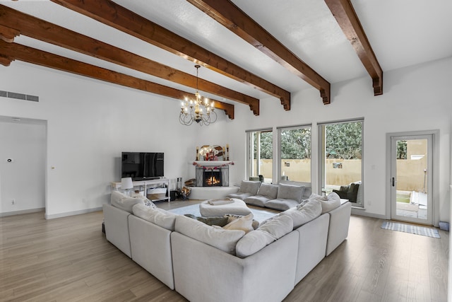 living room featuring beam ceiling, light hardwood / wood-style flooring, and a chandelier