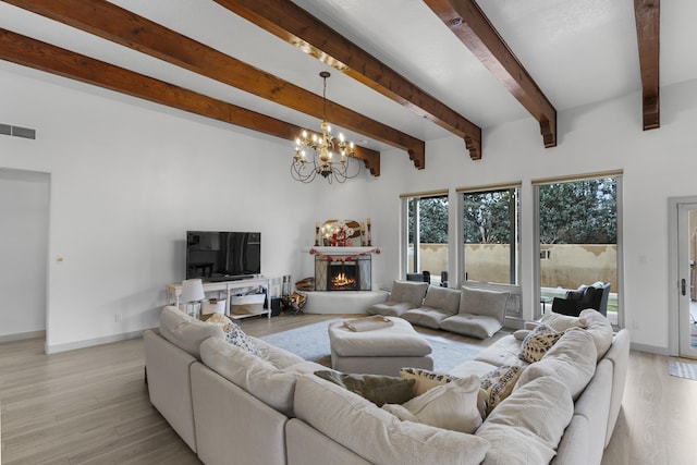 living room featuring beam ceiling, light hardwood / wood-style flooring, and a chandelier