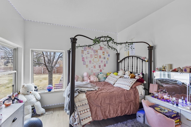 bedroom with vaulted ceiling and light wood-type flooring