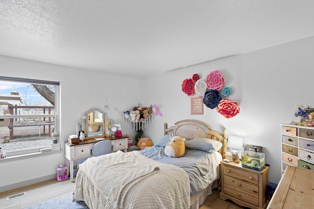 bedroom with a textured ceiling and light hardwood / wood-style floors