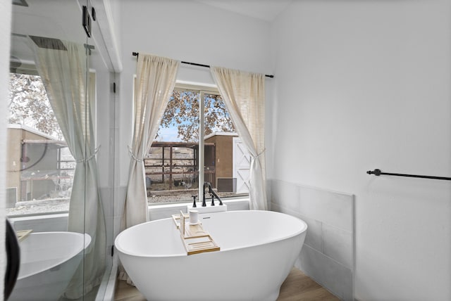 bathroom featuring tile walls, hardwood / wood-style floors, and a bathing tub