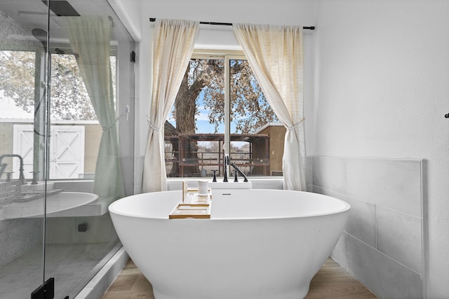 bathroom with hardwood / wood-style floors, a tub, and tile walls