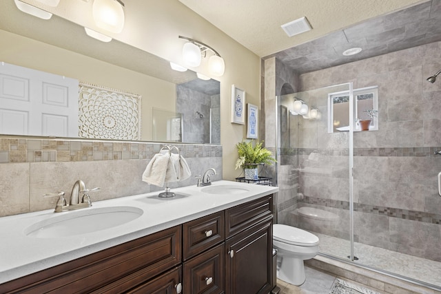 bathroom with vanity, a shower with shower door, a textured ceiling, and toilet