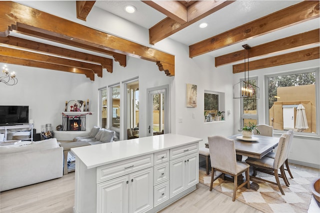 kitchen featuring hanging light fixtures, beam ceiling, a center island, white cabinets, and a chandelier