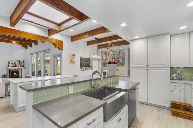 kitchen with white cabinetry, beam ceiling, and a kitchen island with sink