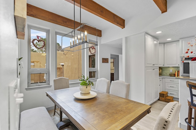 dining space featuring beamed ceiling, a notable chandelier, and light wood-type flooring