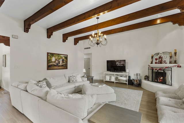 living room with a notable chandelier, beam ceiling, and light wood-type flooring