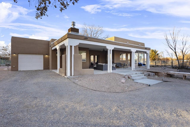 back of house with a garage, an outdoor hangout area, and a patio area