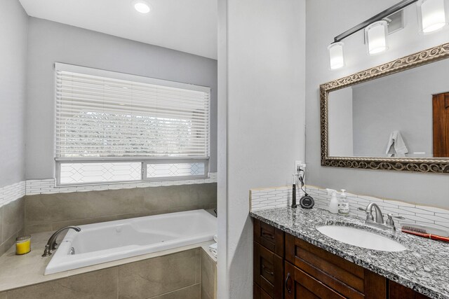 bathroom with vanity and tiled tub