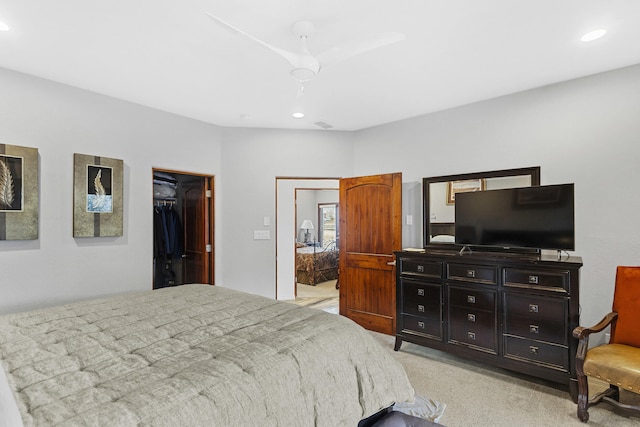 bedroom with a spacious closet, light colored carpet, a closet, and ceiling fan