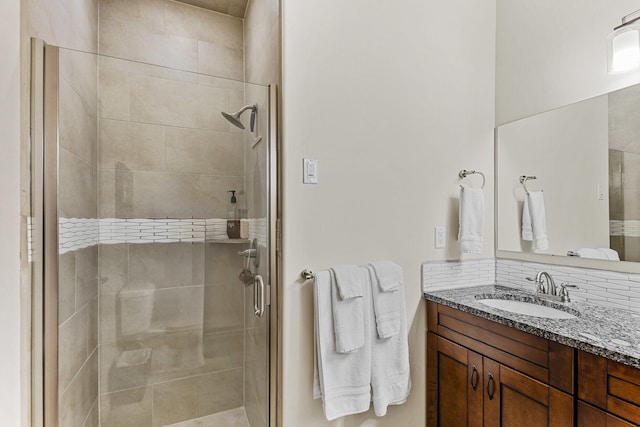 bathroom featuring vanity, a shower with shower door, and tasteful backsplash