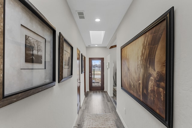 corridor with hardwood / wood-style floors and a skylight