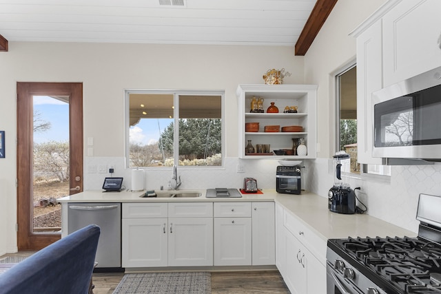 kitchen featuring a wealth of natural light, white cabinetry, sink, stainless steel appliances, and beam ceiling