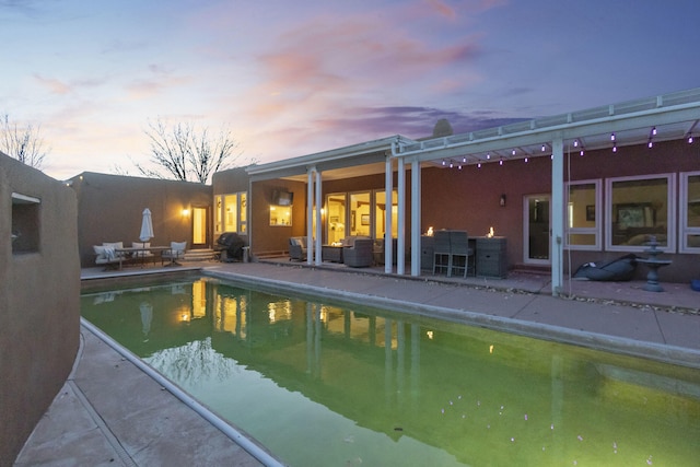 pool at dusk with an outdoor living space and a patio area