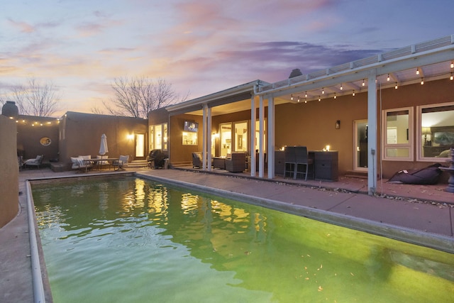 pool at dusk featuring a patio area