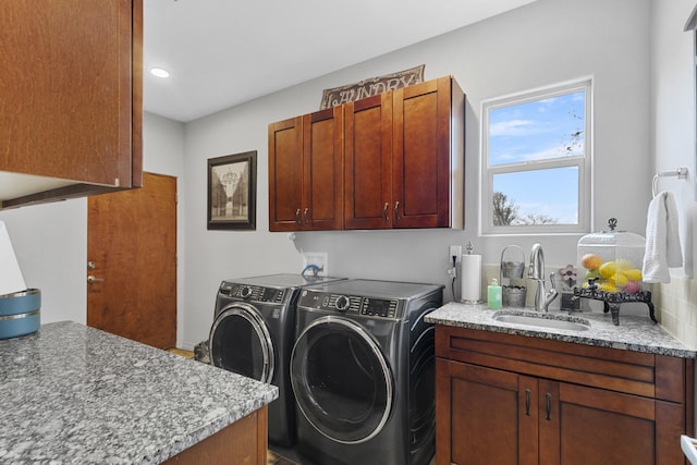 clothes washing area featuring cabinets, sink, and washer and clothes dryer