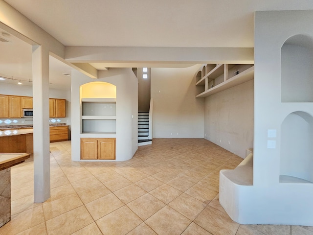 unfurnished living room with stairway, arched walkways, and light tile patterned floors