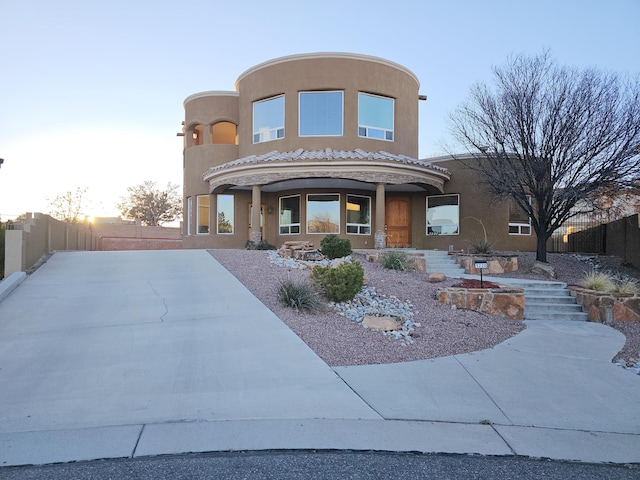exterior space with fence, a tiled roof, and stucco siding