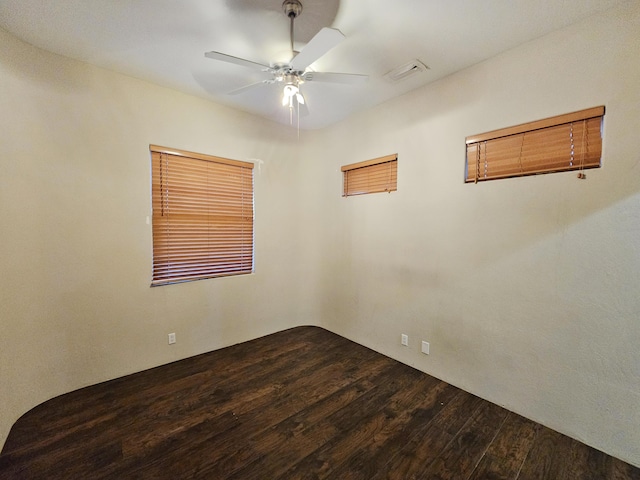 unfurnished room featuring ceiling fan, dark wood-style flooring, and visible vents