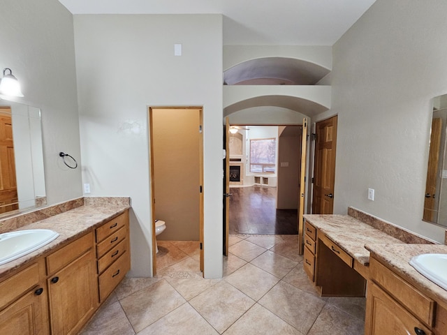 full bath featuring two vanities, a sink, tile patterned flooring, and toilet