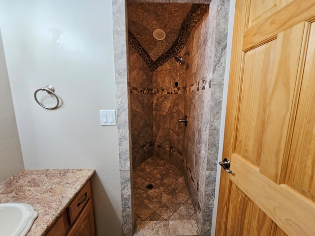 full bath with tiled shower and vanity