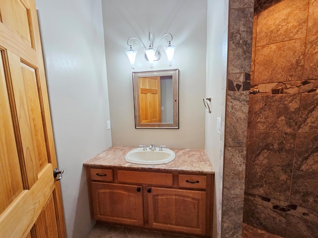 bathroom with tiled shower and vanity