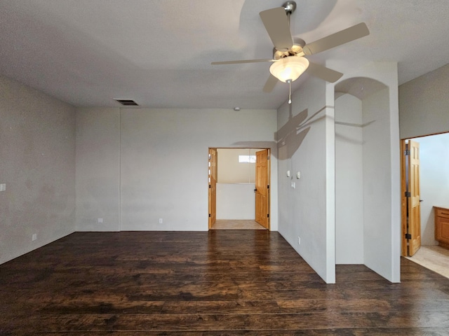 unfurnished room featuring ceiling fan, dark wood finished floors, and visible vents