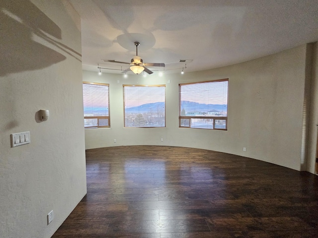 empty room featuring hardwood / wood-style flooring, ceiling fan, track lighting, and visible vents