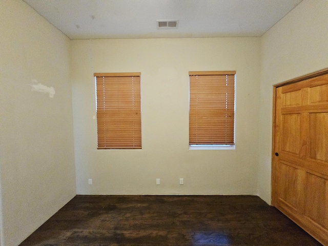unfurnished room with wood finished floors and visible vents