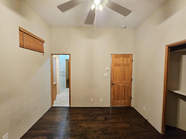 unfurnished room featuring dark wood-style floors, a towering ceiling, and a ceiling fan