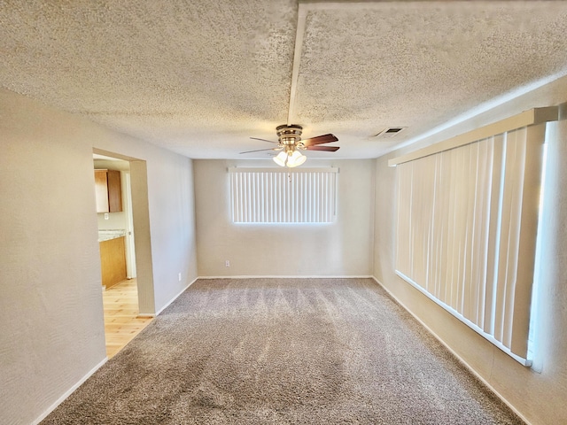 spare room with visible vents, carpet flooring, ceiling fan, a textured ceiling, and baseboards