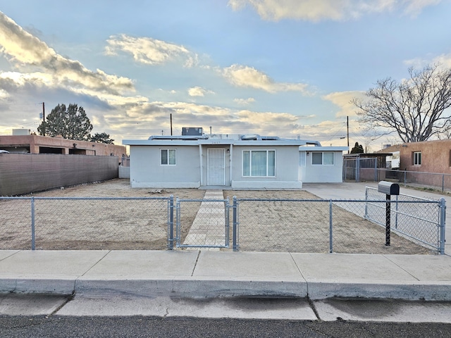 view of front of house featuring a fenced front yard, a gate, solar panels, and stucco siding