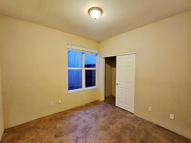 unfurnished bedroom featuring concrete floors and a closet