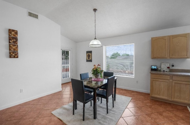 dining space with lofted ceiling, a textured ceiling, and light tile patterned floors