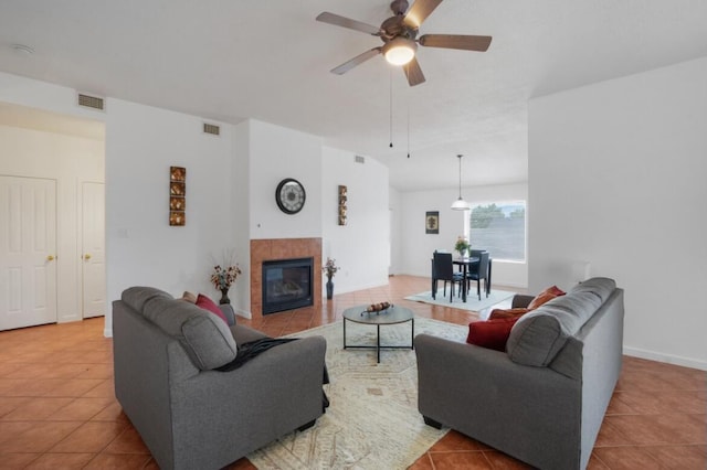 tiled living room featuring a fireplace and ceiling fan