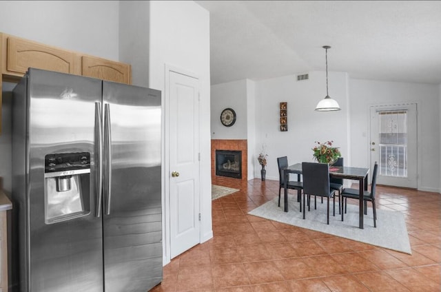 kitchen with a tile fireplace, tile patterned flooring, hanging light fixtures, stainless steel refrigerator with ice dispenser, and vaulted ceiling