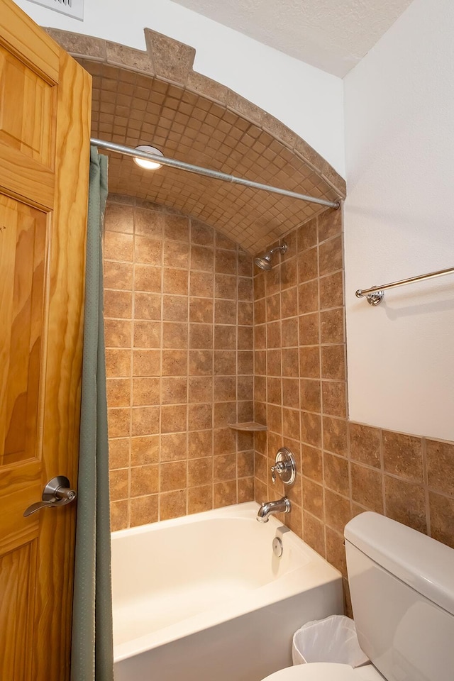 bathroom featuring shower / bath combination with curtain and toilet