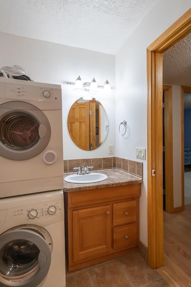 bathroom with vanity, tile patterned flooring, a textured ceiling, and stacked washing maching and dryer