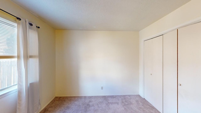 unfurnished bedroom with light colored carpet and a closet